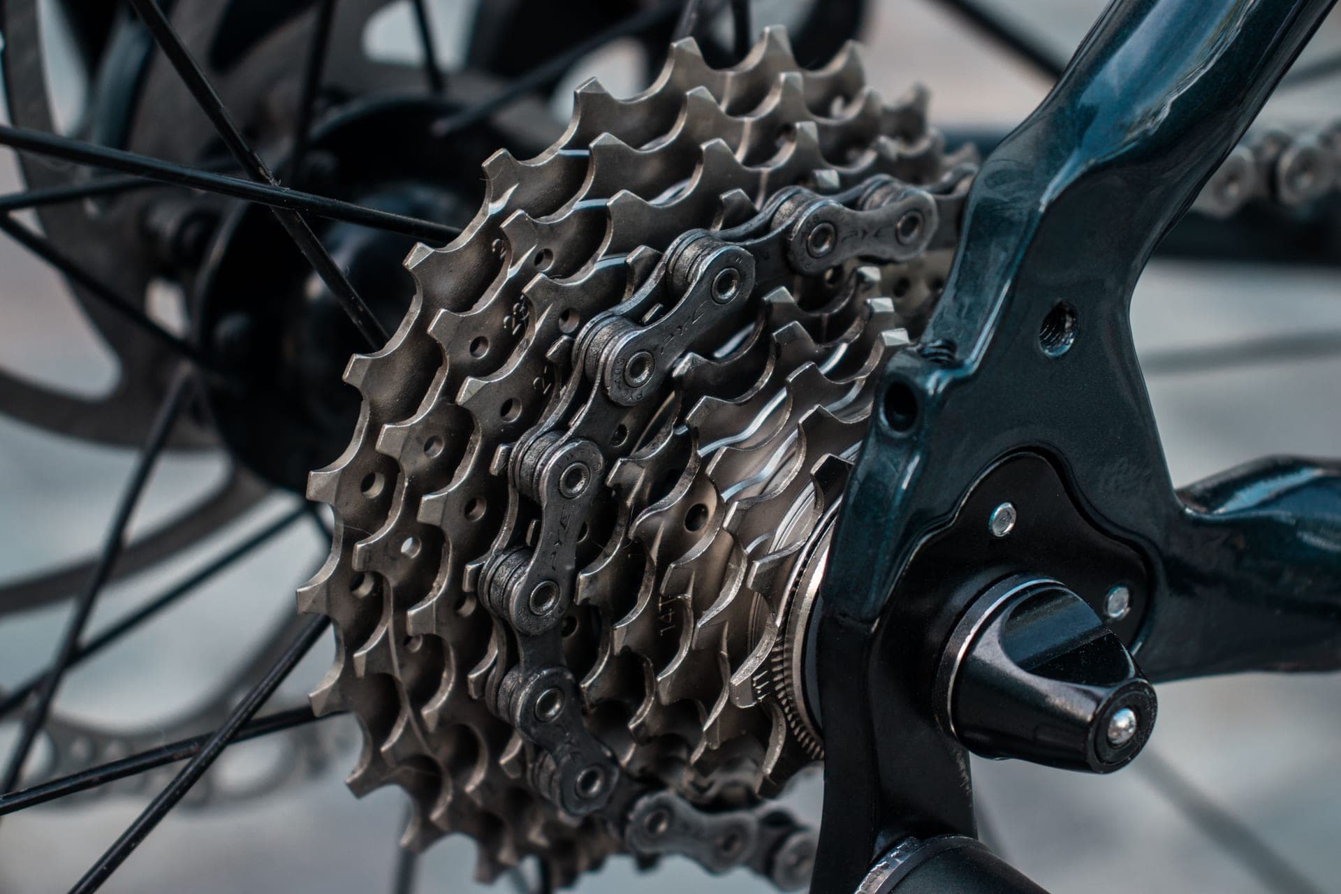 A road bike rear cassette and derailleur in raking light, the cogs stacked across the freehub.