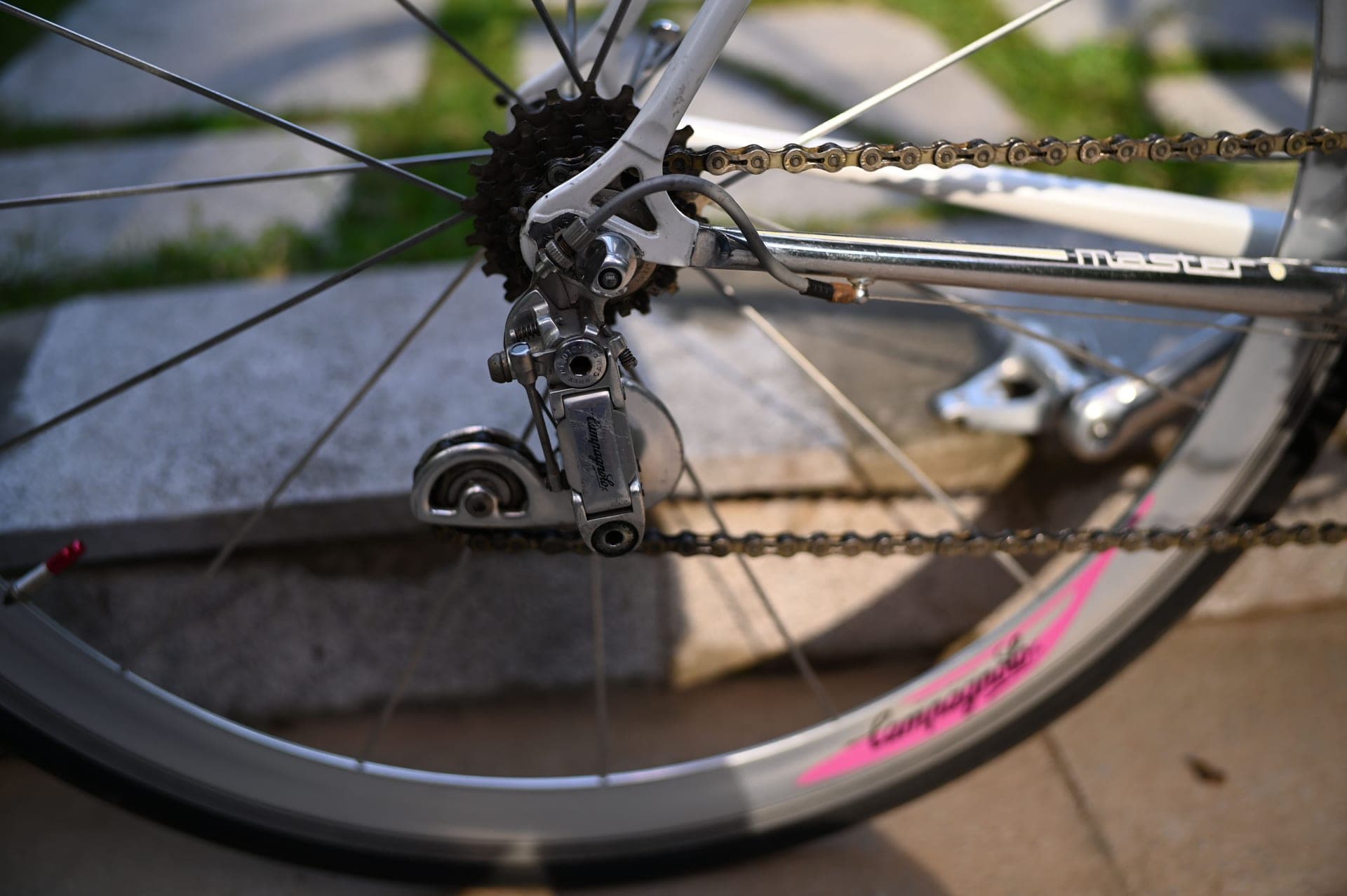 Close crop of a road bike rear derailleur and cassette in hard directional light.