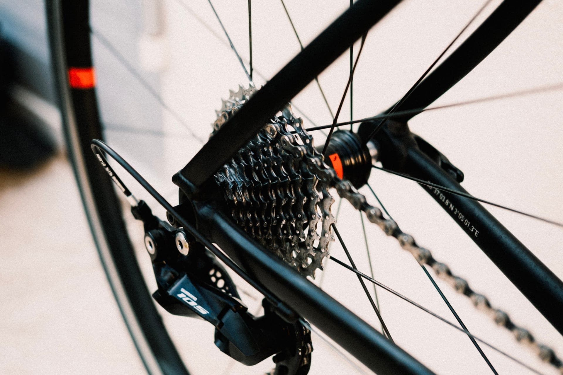 A road bike drivetrain with the rear derailleur and cassette catching hard side light.