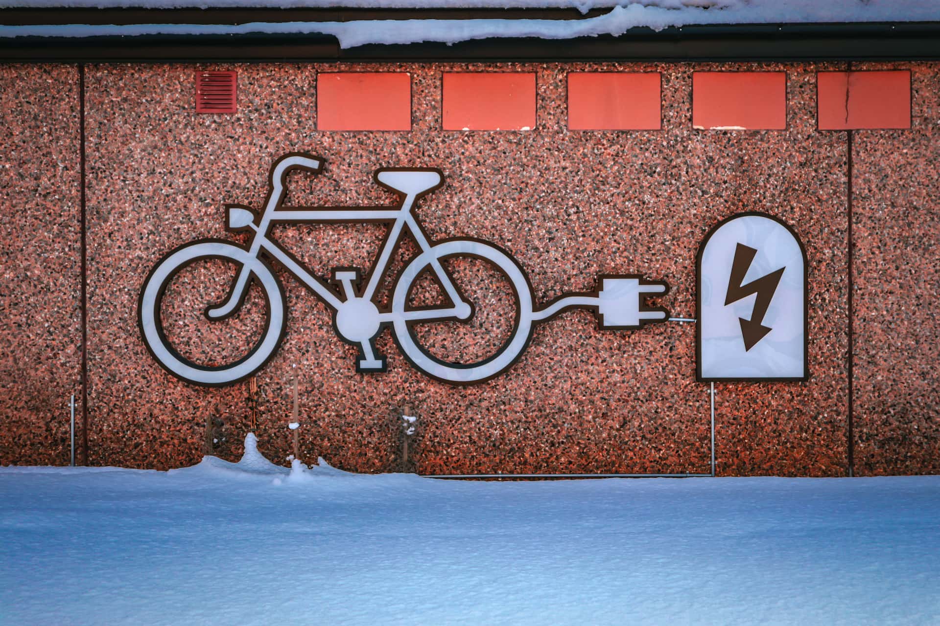 An electric commuter bike parked against a wall in a city street at dusk.