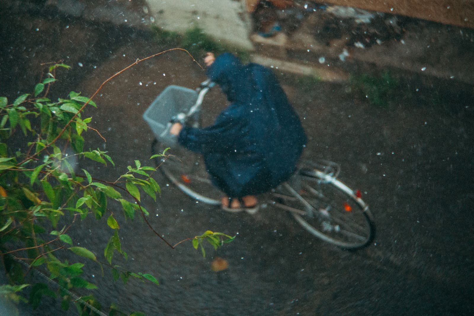 A cyclist riding on a wet road in heavy rain.