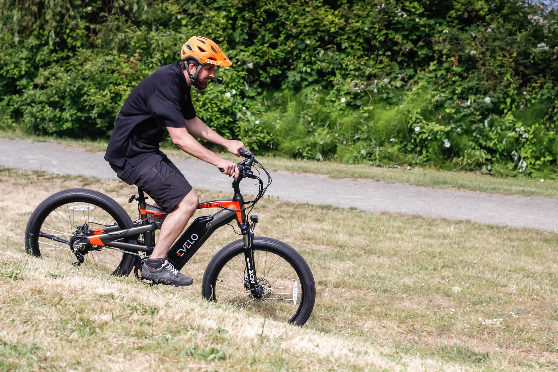 A rider pedalling an electric bicycle on a road in daylight.
