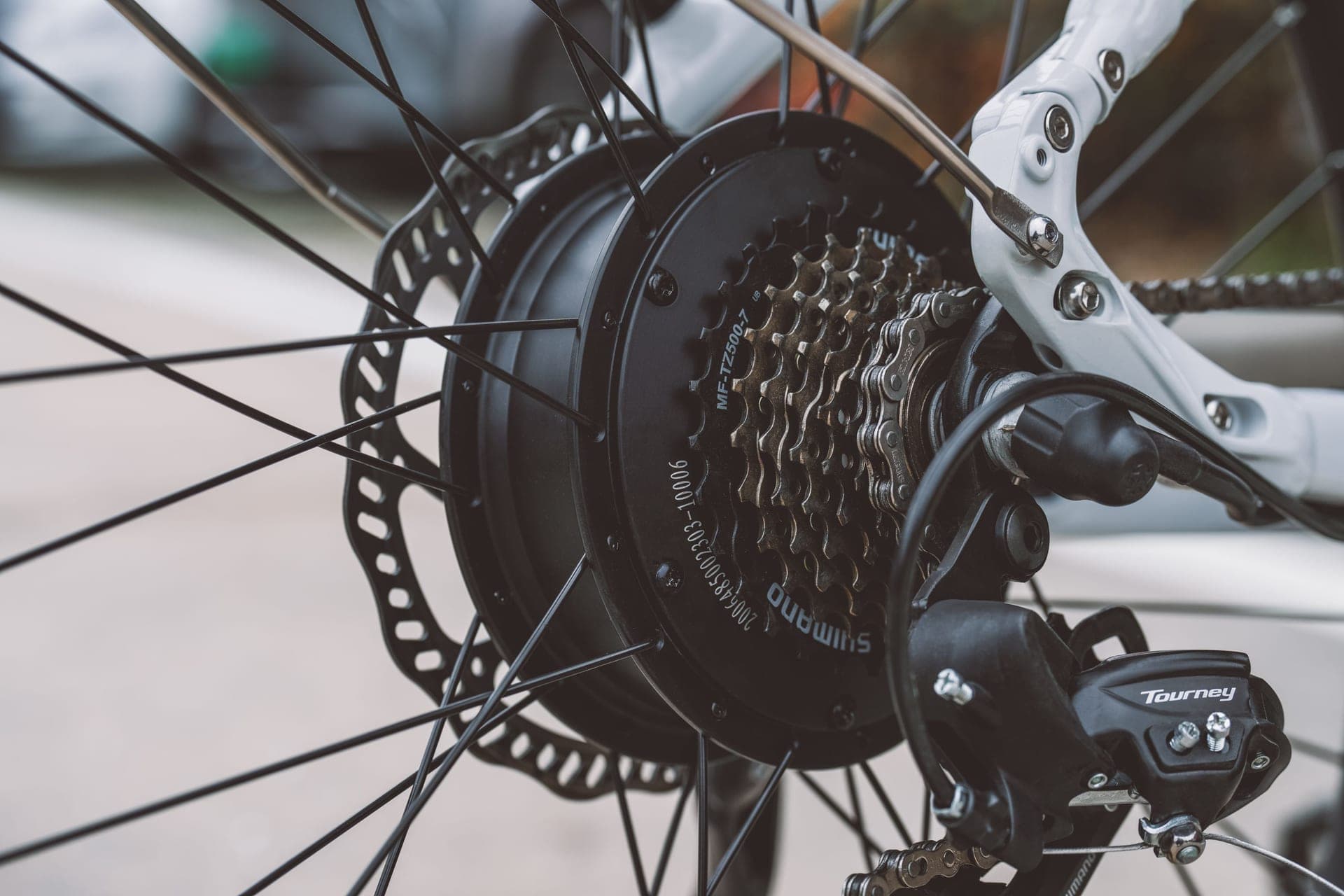 A rear hub motor, disc rotor and derailleur on a converted bicycle.