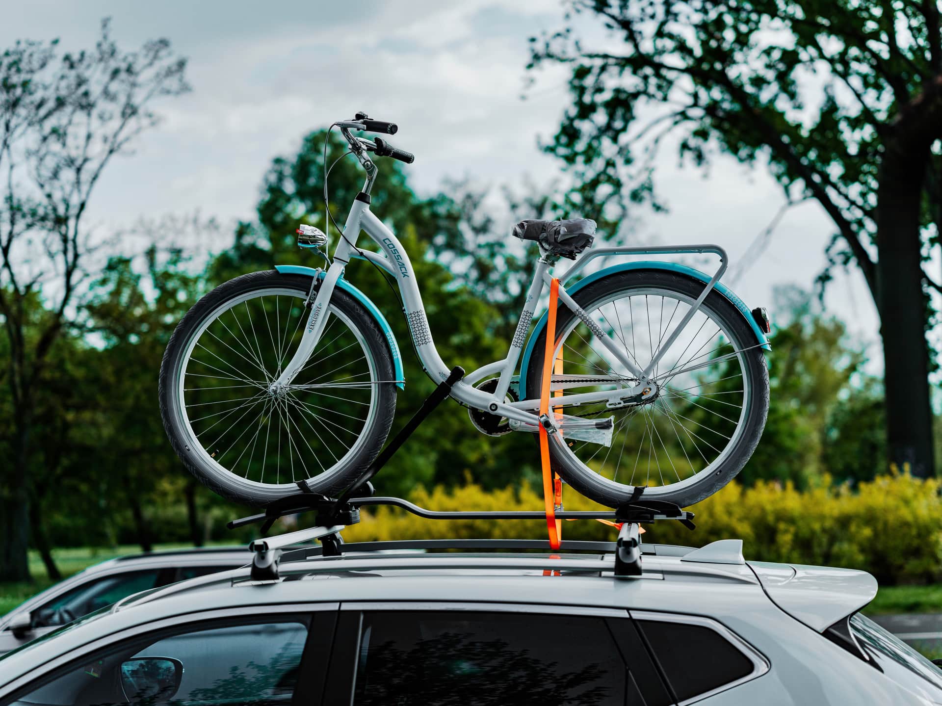 A bicycle secured to a car rack on a scenic road.