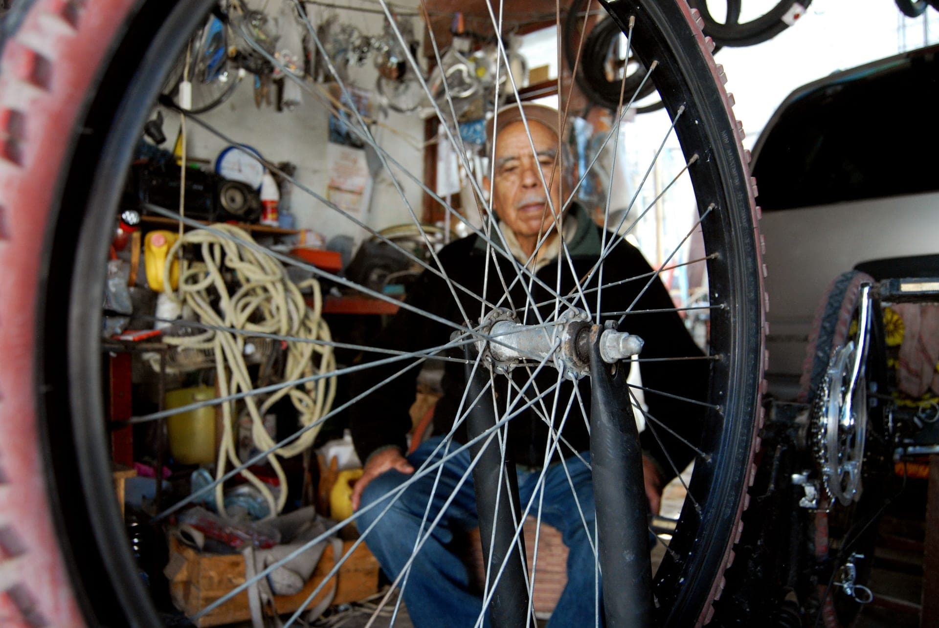 A gravel bike wheel and tubeless tire on a workshop bench beside a sealant bottle and a valve.