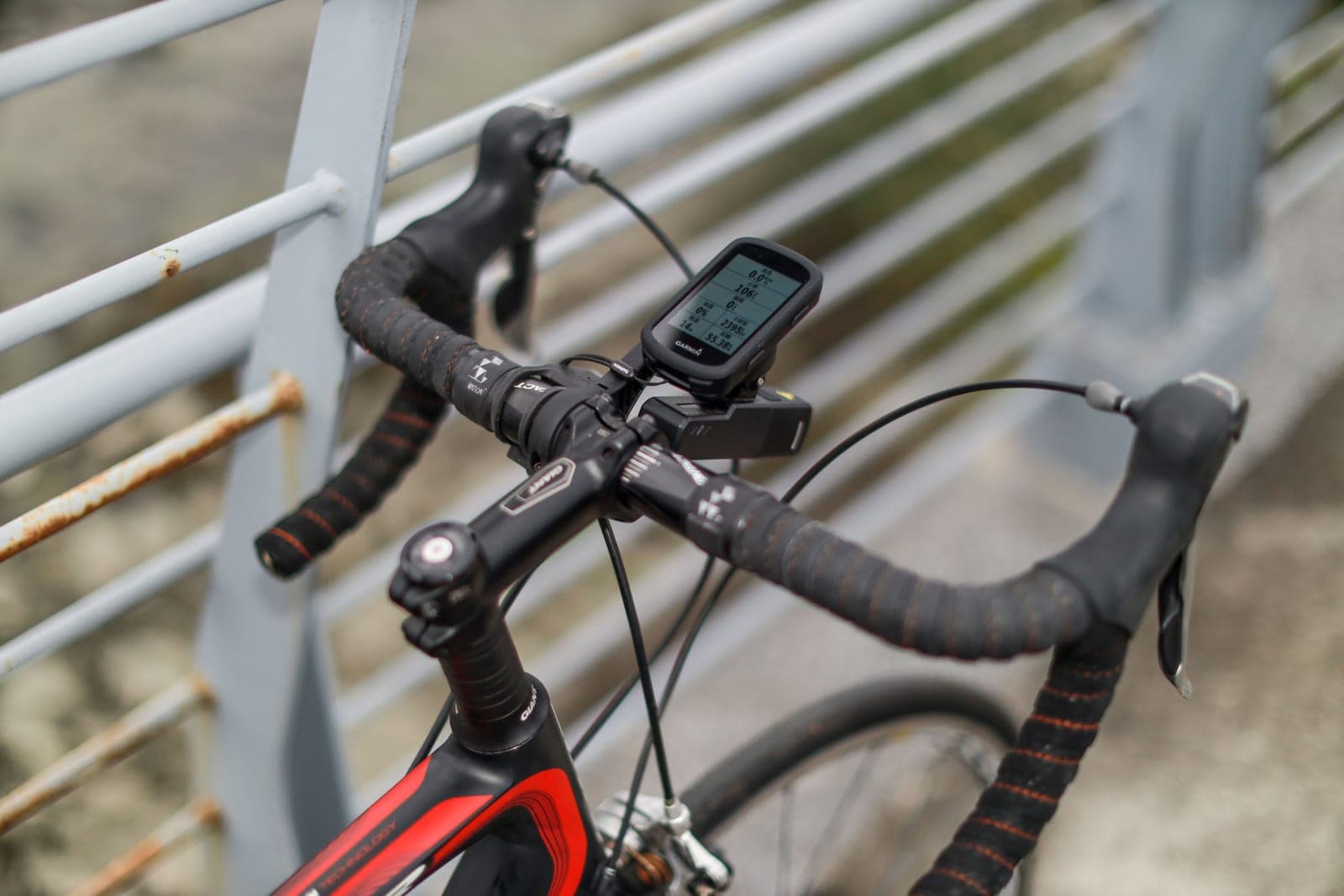 A bicycle handlebar with a GPS bike computer mounted, photographed close up in an urban street.