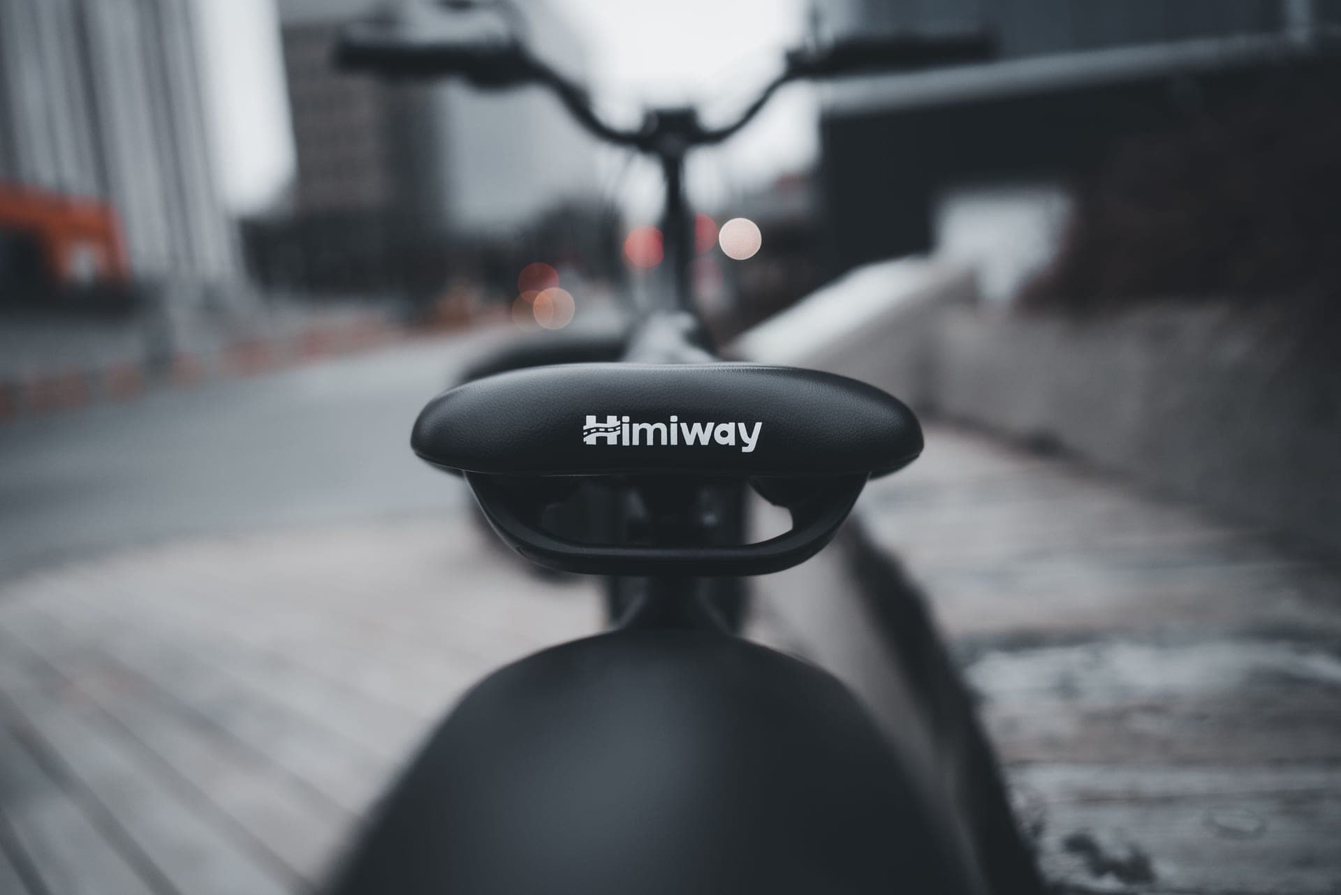 A road bike saddle photographed from behind against a plain, hard-lit background.
