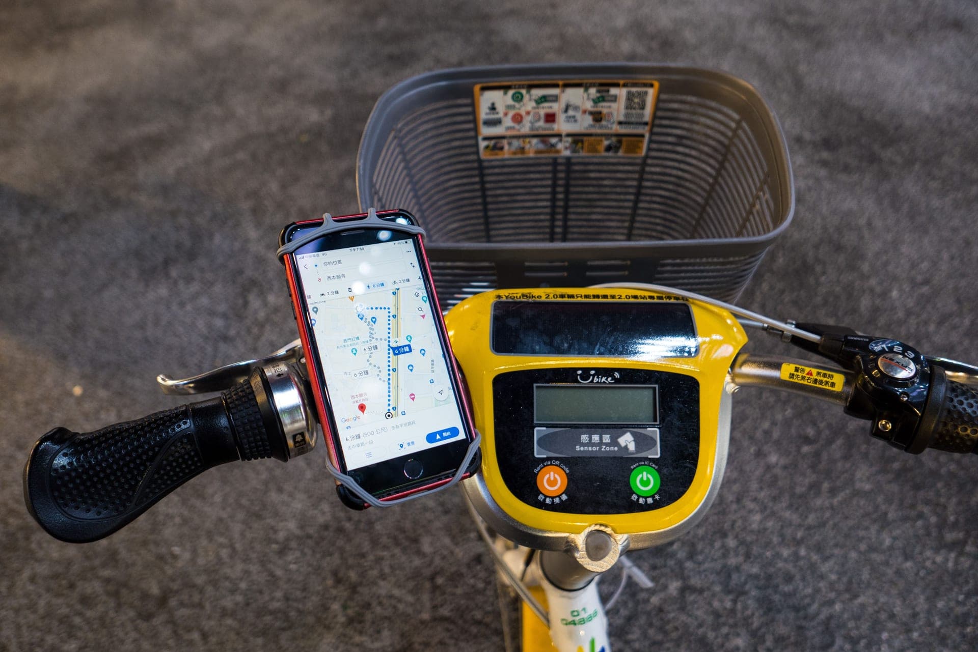A smartphone showing a map, mounted on bicycle handlebars.