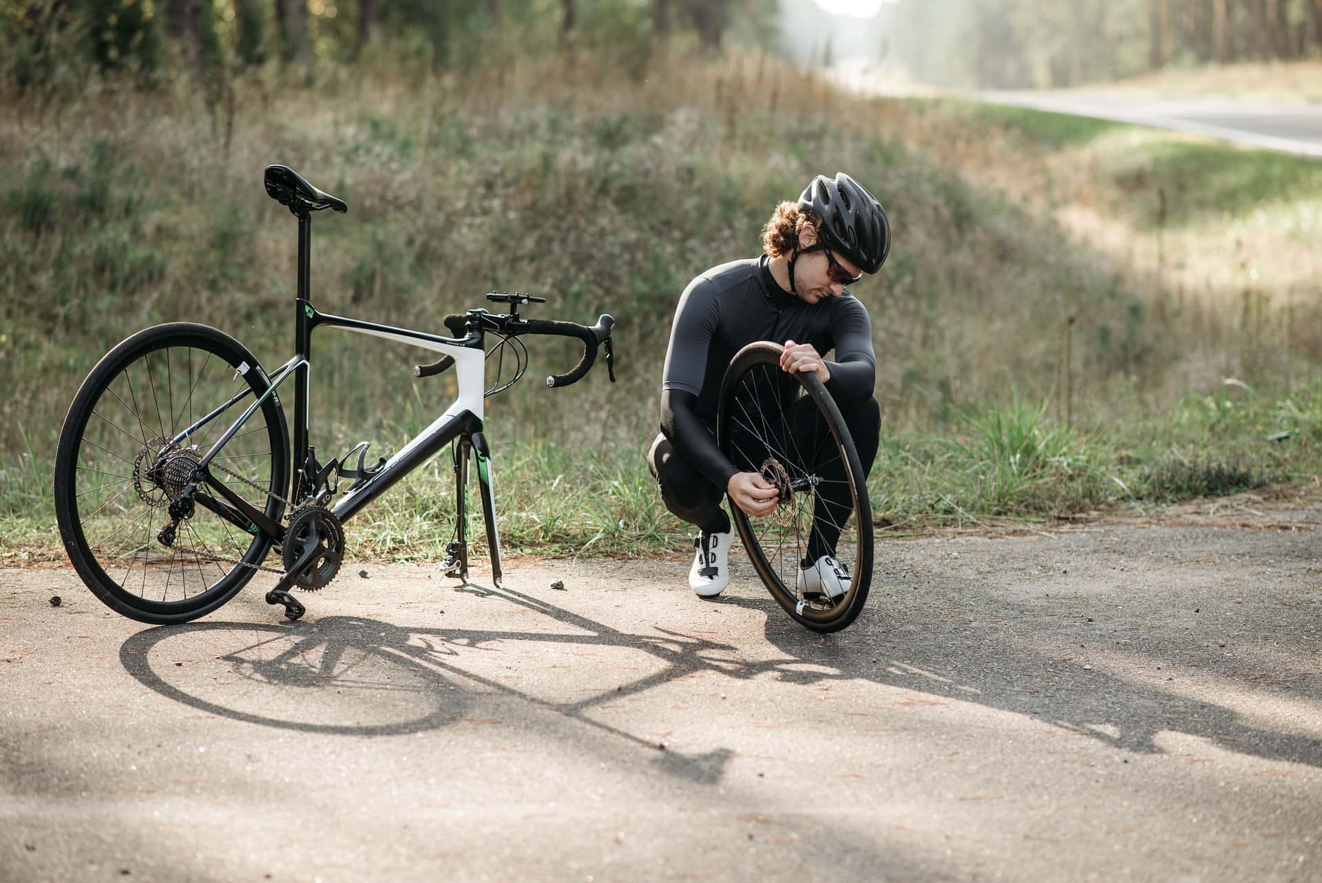 A bicycle wheel with tire levers engaged under the tire bead at the roadside.