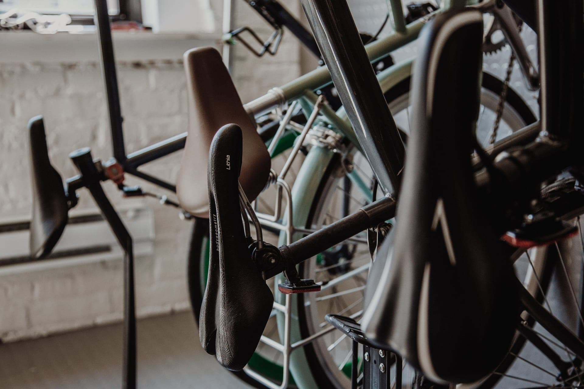 Several bicycles hung by their front wheels from wall hooks in a dim garage.