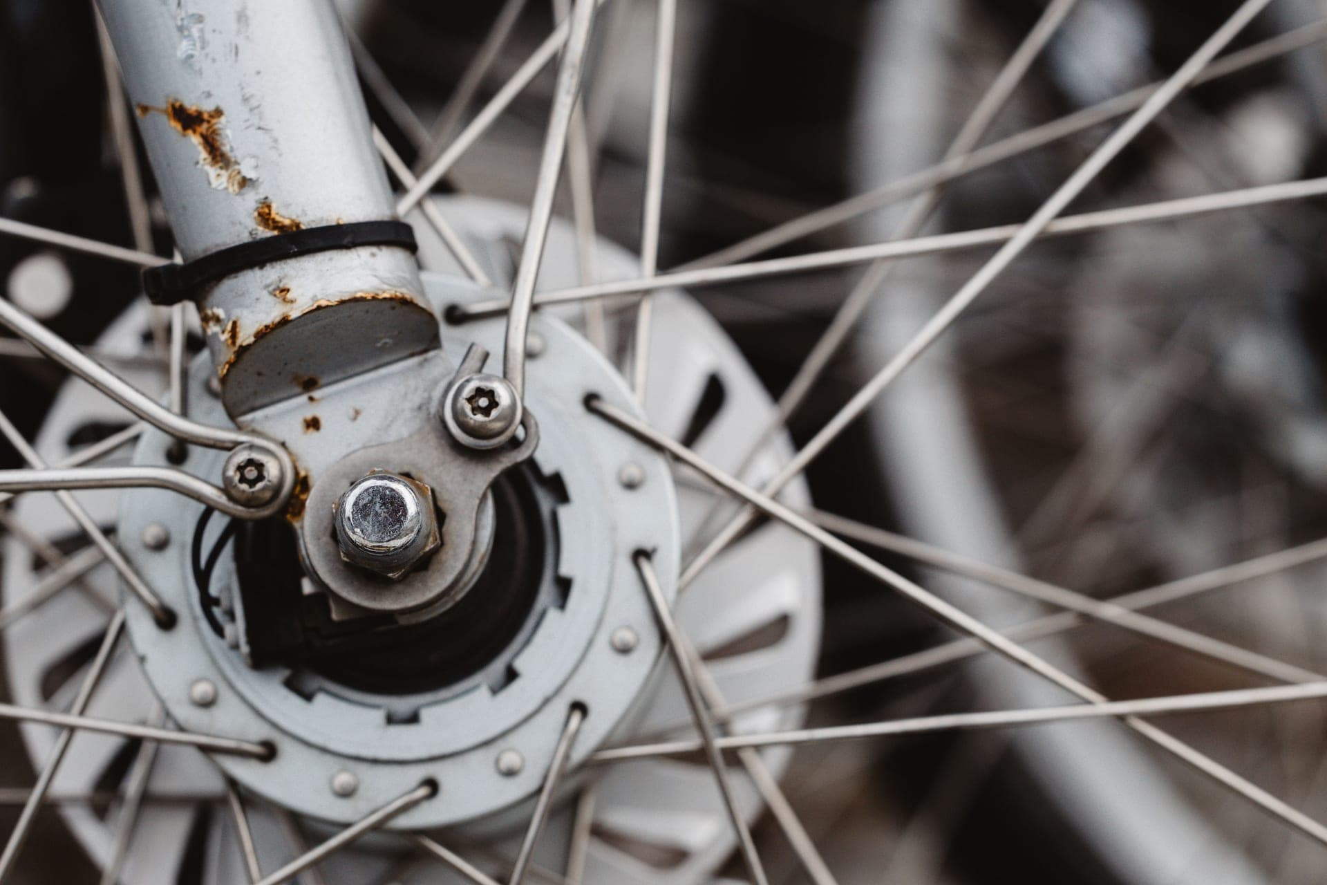 A bicycle rear wheel spinning in a truing stand with a spoke wrench resting against the rim.