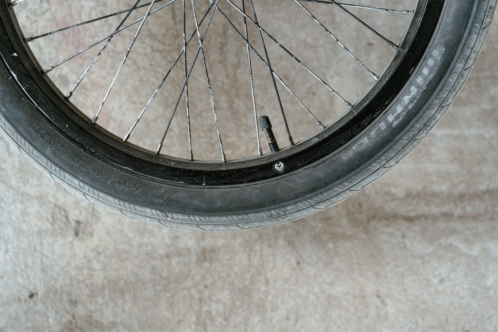 Close-up of a bicycle wheel showing the spokes and the valve at the rim.