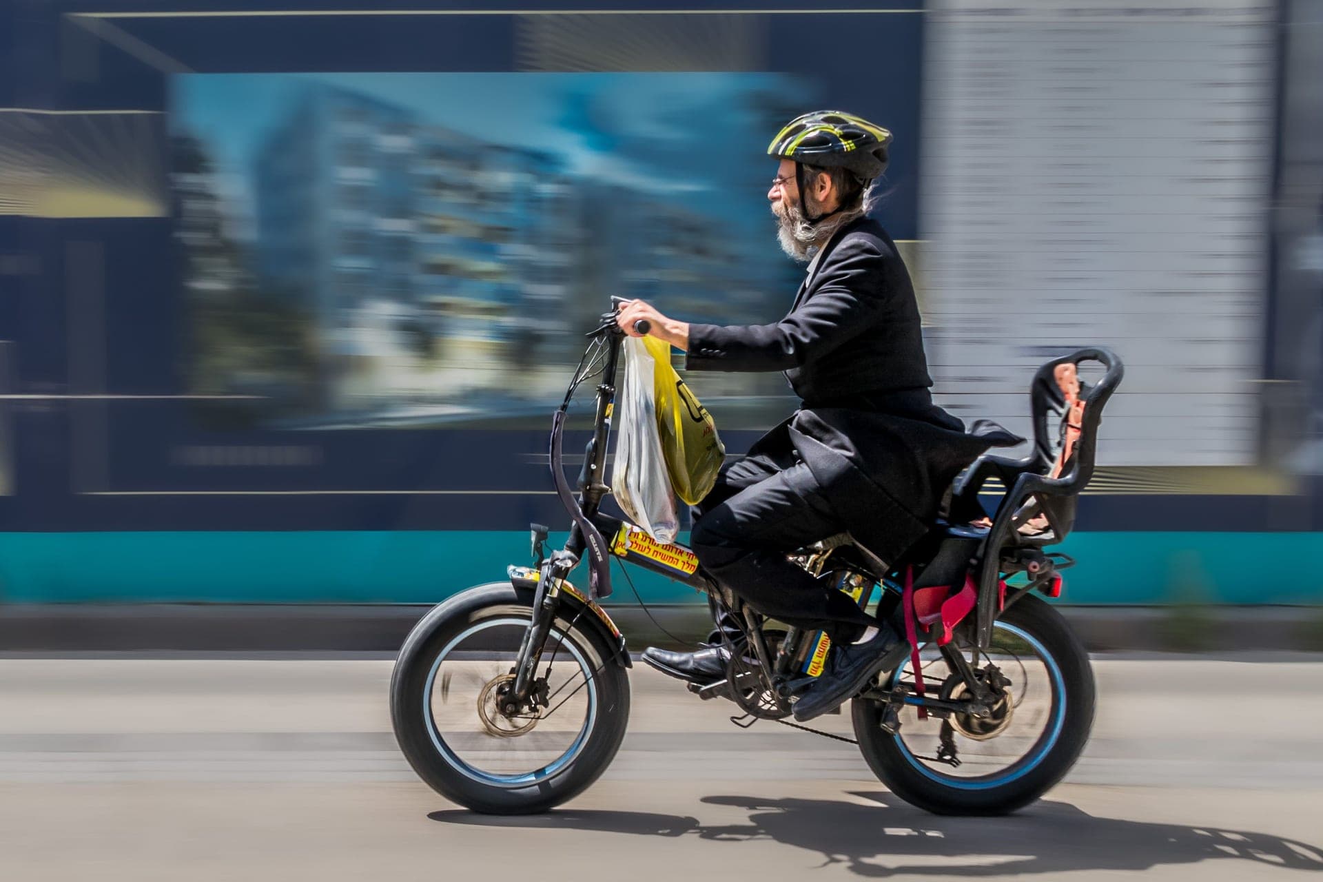 A rider on an electric bike on an urban street at dusk.