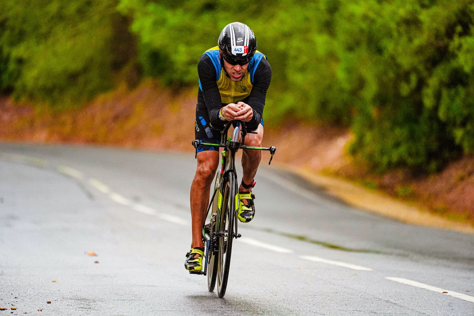 A road cyclist riding on wet tarmac in low sun.